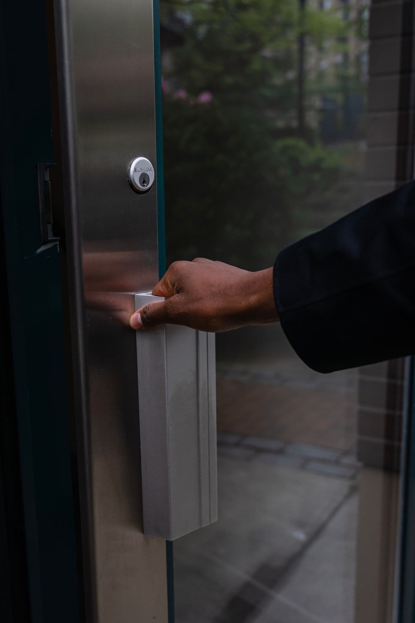 Hand opening a commercial glass door with metal pull hardware